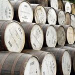 Outdoor rows of premium whisky barrels, each with distinctive white ends adorned with numbers and inscriptions, highlight the high-value investment quality of this brand.
