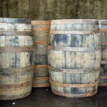 A row of premium aged whisky barrels is set against a rich, textured backdrop, evoking a sense of high-value investment quality.