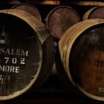 In a dimly lit cellar, wooden barrels inscribed with "Matusalem Dalmore 2006" and "Gonzalez & Byass No. 571" are meticulously stacked, ideal for enthusiasts interested in Dalmore cask whisky investment and high-value whisky brands.