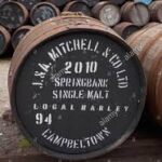 The wooden cask labeled "2010 Springbank Single Malt Local Barley" stands prominently among other barrels against a striking black background with crisp white text. Perfect for whisky investment enthusiasts, this barrel embodies the timeless allure and craftsmanship of high-value Springbank whisky, making it an exceptional addition to any fine spirits portfolio.