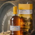Artfully displayed in front of a wooden barrel, the prestigious Tobermory 23 Single Malt Scotch Whisky and its elegant box capture the essence of high-value whisky investments, ideal for enthusiasts considering cask investment strategies.