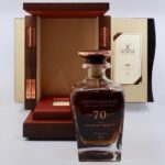 A luxurious GlenGrant 70-year-old single malt whisky bottle, a prized investment for collectors, is elegantly showcased before an open wooden display box adorned with copper accents.