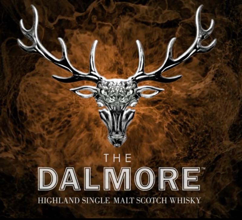 Centered on a rich, swirling brown background is a silver stag head logo with large antlers, symbolizing prestige and investment potential. Below, the text reads: "The Dalmore - Highland Single Malt Scotch Whisky," showcasing its high-value brand status in whisky investing.