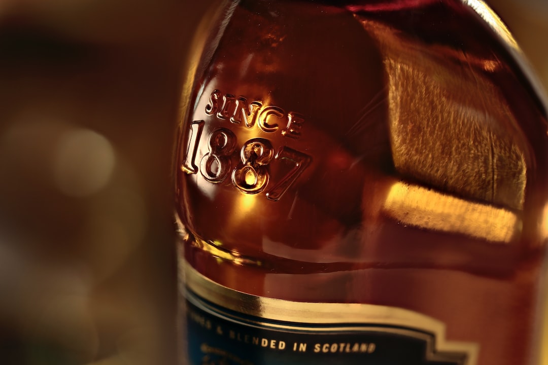 A close-up of a premium whisky bottle, embossed with "Since 1887," showcases the rich amber liquid inside and hints at its high-value brand with a partially visible elegant label.