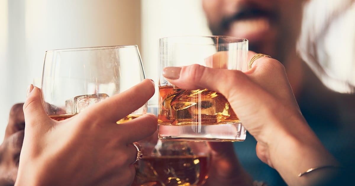 people clinking glasses with whisky toast