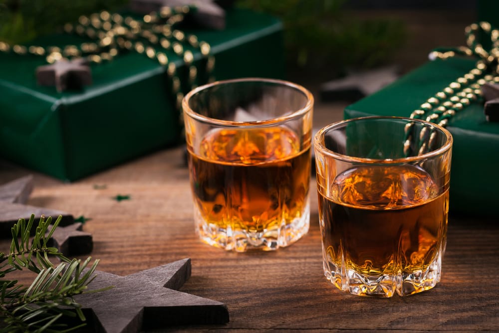 Two shot glasses of whiskey or bourbon with Holiday decoration