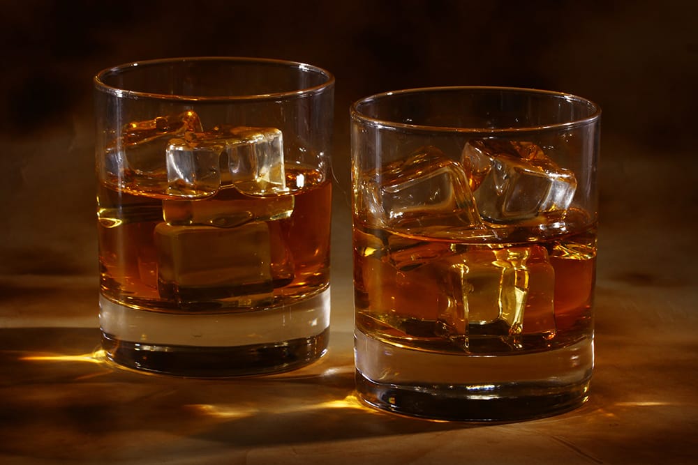 2 whisky glasses with cold whisky on table