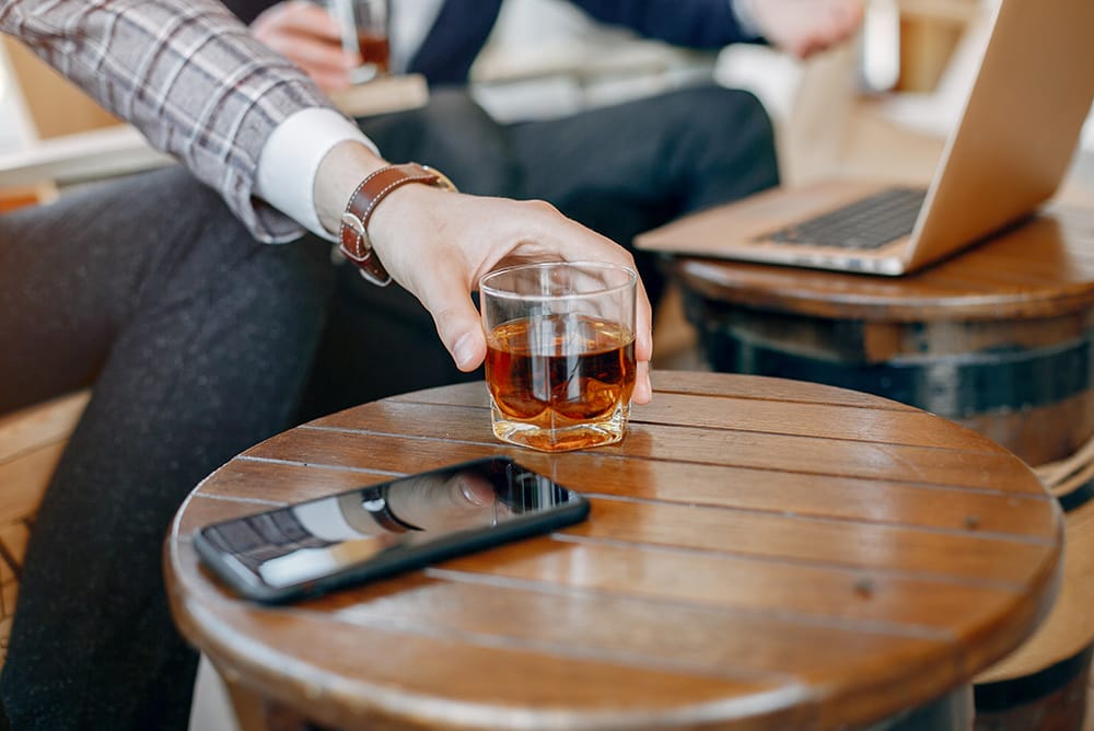 businessman with mobile phone and whisky glass