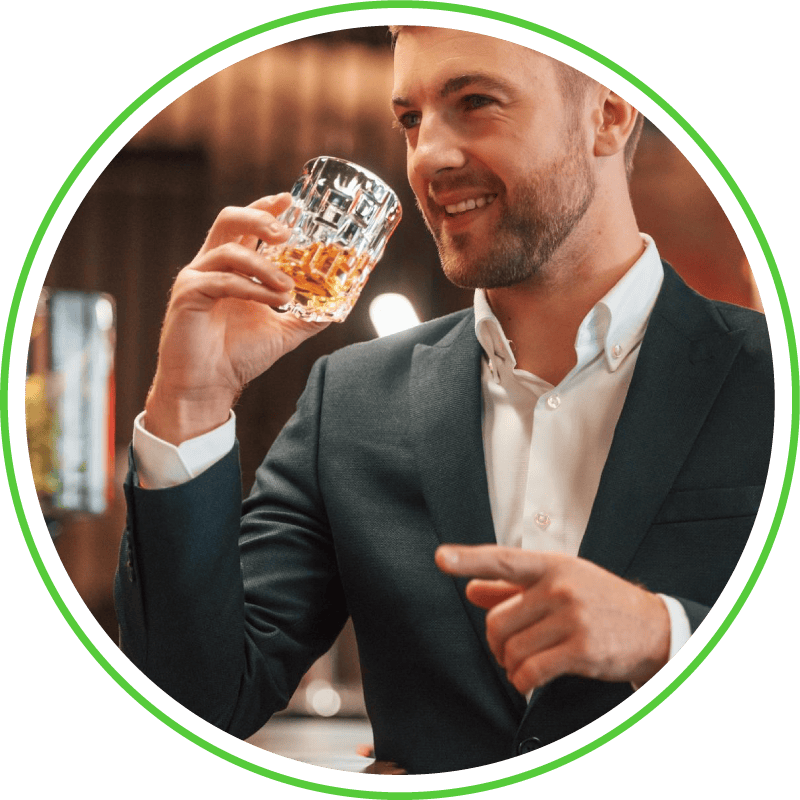 A well-dressed man enjoys a fine glass of whisky and smiles, highlighting premium whisky investment in an elegant indoor setting.