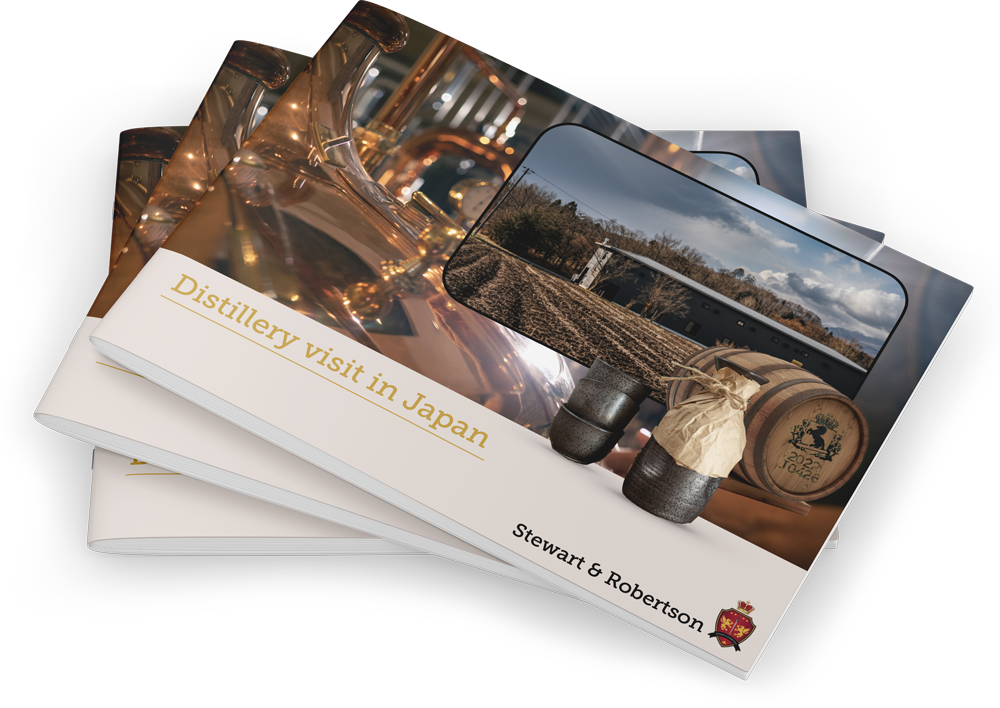 A stack of premium whisky booklets titled "Distillery visit in Japan" shows iconic equipment, barrels, and Japanese whisky scenes.