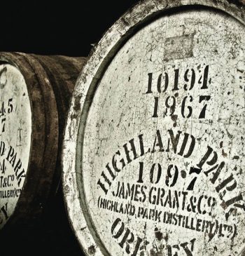 This image features a close-up of weathered oak barrels labeled "Highland Park," showcasing production dates and numbers that highlight whisky maturation and age. This representation underlines the high-value investment quality typical of premium whisky brands.